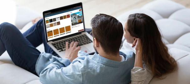 couple sitting on couch using laptop with garage door visualizer open